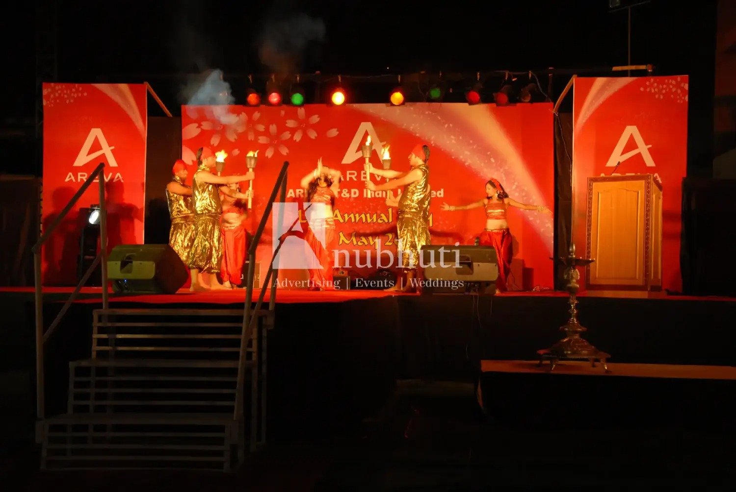 Man and woman speaking on stage at night with blue lighting